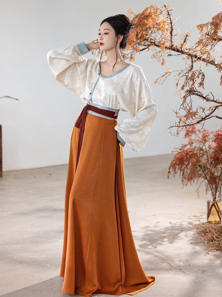 Side view of modern Tang style Hanfu clothing with puffed lantern sleeves, contrasting waist sash, blue trim, and flowing orange skirt