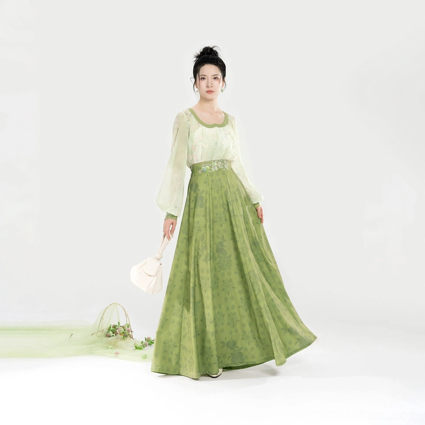 Modern Tang Dynasty Hanfu set shown in a graceful walking pose with an off-white lightweight top, sage green floor-length skirt, and flowing eight-panel silhouette