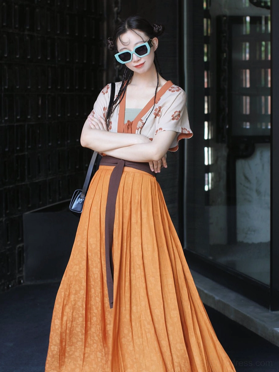 Side view of a relaxed modern Tang Dynasty hanfu set with short beizi vest and flowing orange pleated skirt