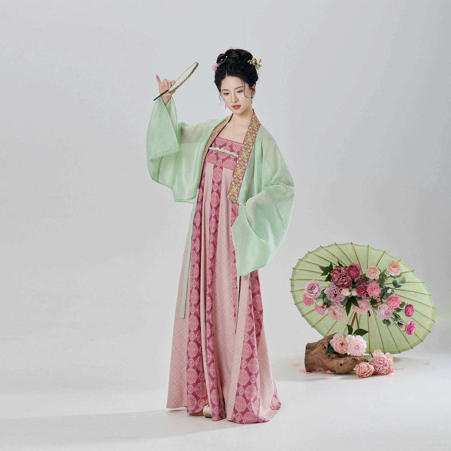 Three-quarter side view of modern Tang Dynasty Hanfu dress set with flowing sleeves styled with a traditional folding fan