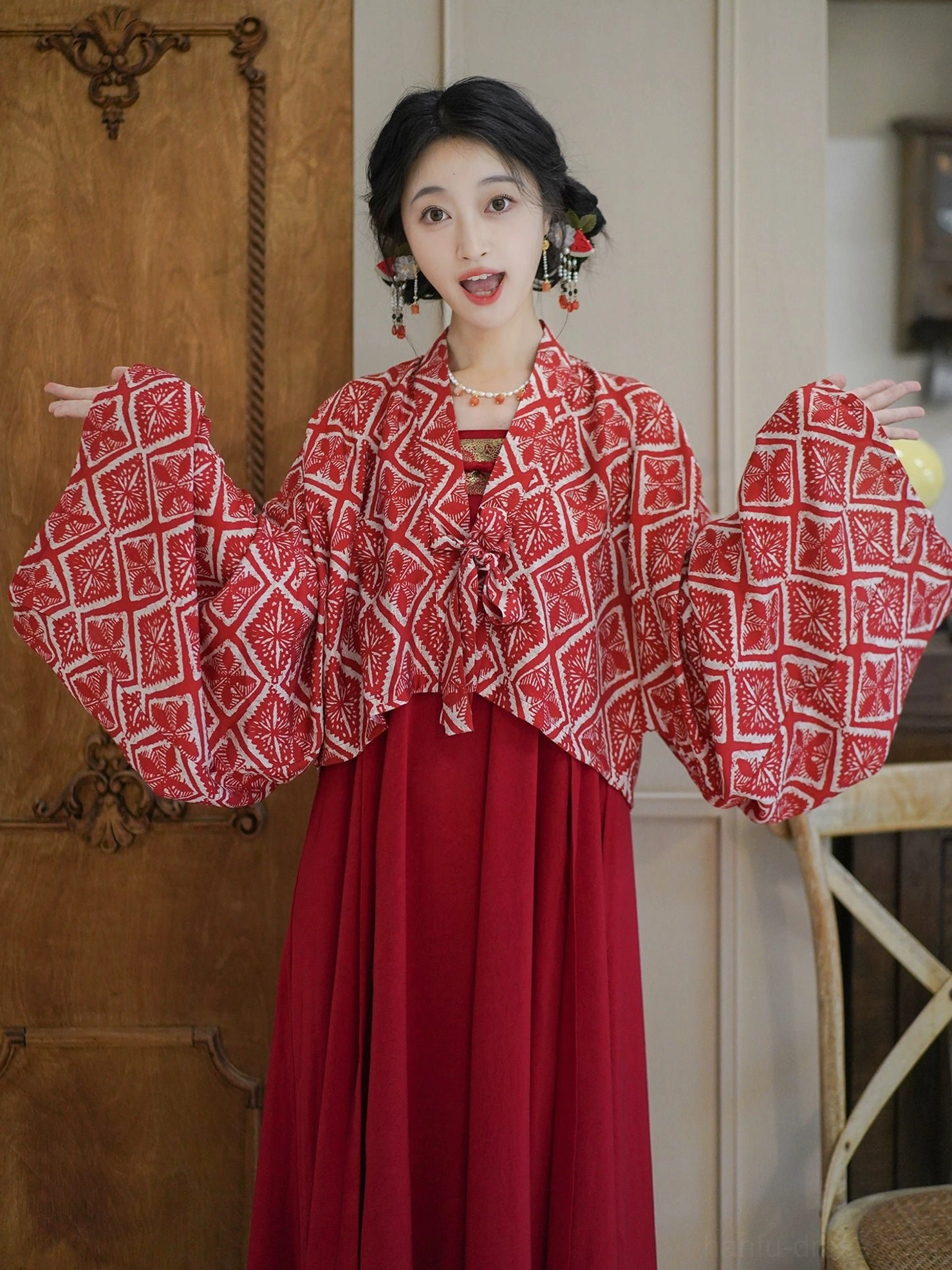 Modern Tang Dynasty Hanfu model displaying the wide sleeves and front sash ties of a cropped geometric print cardigan over a wine-red dress
