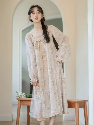 Model wearing an apricot modern Tang style floral Hanfu dress with square neckline front bow ruffled lantern sleeves and side split midi hem in a vintage indoor setting