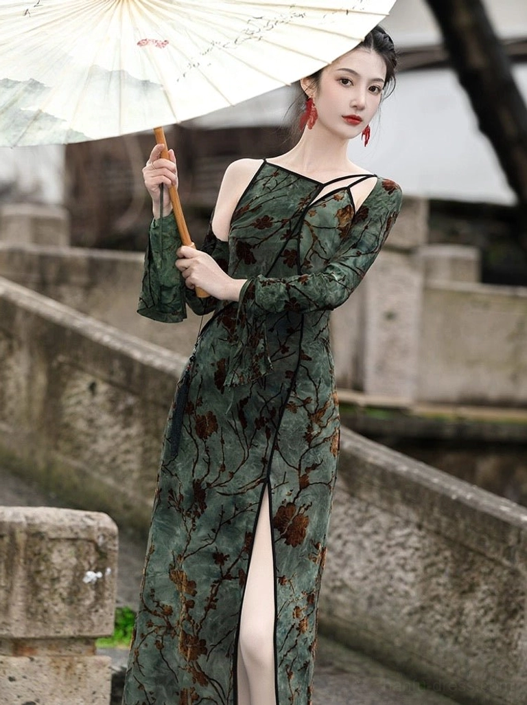 Modern dark green Tang style Hanfu dress with brown floral print, asymmetrical neckline, black trim, high side slit, and detachable flared sleeves modeled beside a Jiangnan water town river