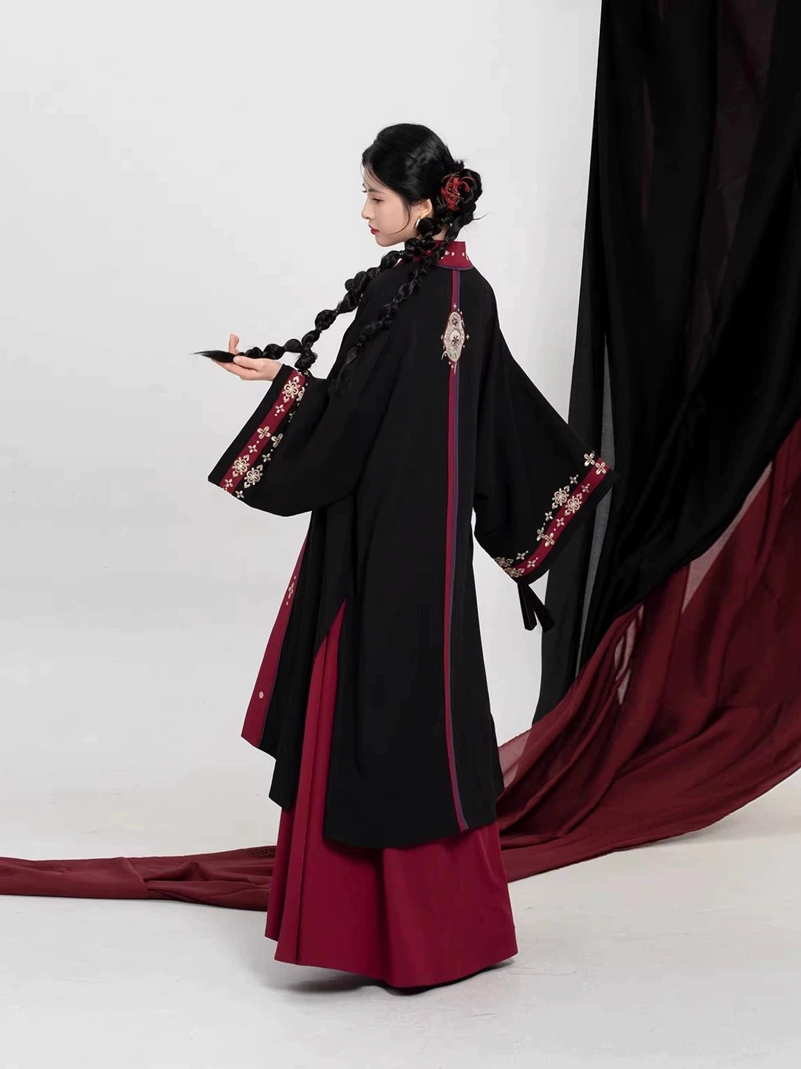 Side back view of a modern Tang-style Hanfu set showing the long black Beizi jacket, embroidered back neckline detail, and matching crimson scarlet dress