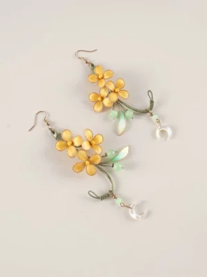 Moon laurel osmanthus drop earrings with yellow flower clusters green leaves crescent moon pendants and rose gold hook ear wires on an off white background