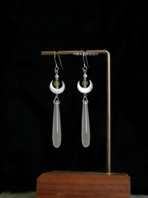 Moon Over Sea Chinese Hanfu dangle earrings displayed on a jewelry stand with white crescent pendants green jade beads and translucent water-drop charms
