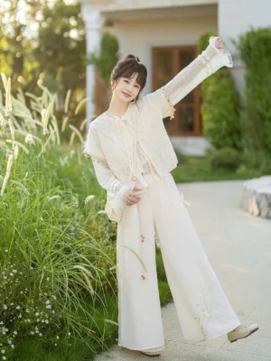 Full front view of a cream Moon Shadow Song Dynasty inspired modern hanfu complete set with cropped round-neck jacket, embroidered wide-leg pants, ruffled cuffs, and tassel details