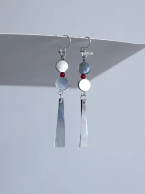 Moon-white mother-of-pearl Chinese dangle earrings with silver hooks, red bead accents, and contrasting gray and white trapezoid shell pendants