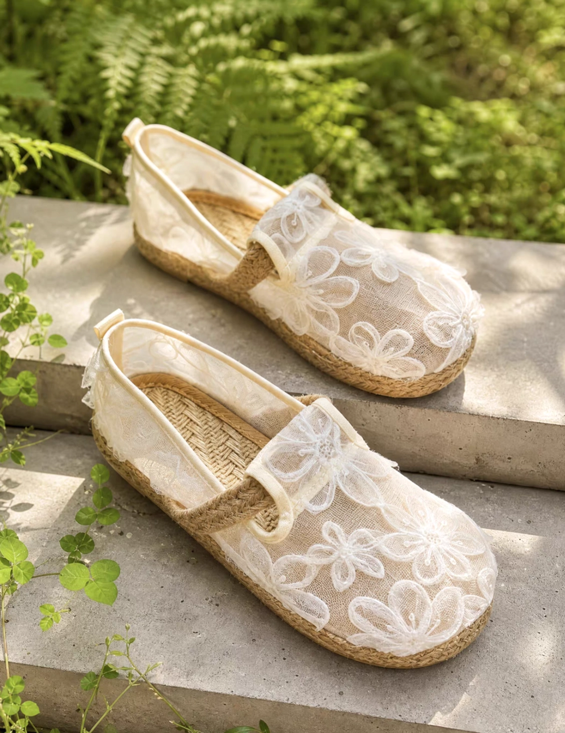 Pair of Morning Dew ivory floral mesh Hanfu espadrille Chinese shoes in a garden setting, showing embroidered uppers, woven insoles and rubber soles