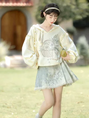 Morning Garden modern Hanfu hooded crop top and short green floral mamian skirt set shown in a garden front three-quarter view