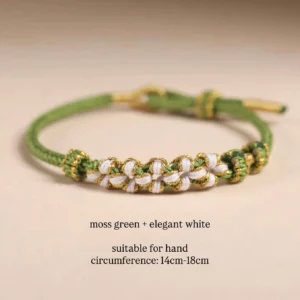 Moss green handwoven Chinese knot bracelet with ivory floral braided details, gold-tone thread accents, and adjustable sliding closure shown on a neutral background