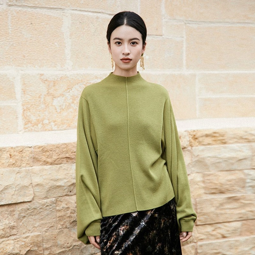 Front low-angle view of a moss green pipa sleeve cashmere blend knitted sweater with relaxed modern Hanfu silhouette, stand collar, front seam, and soft ribbed fabric