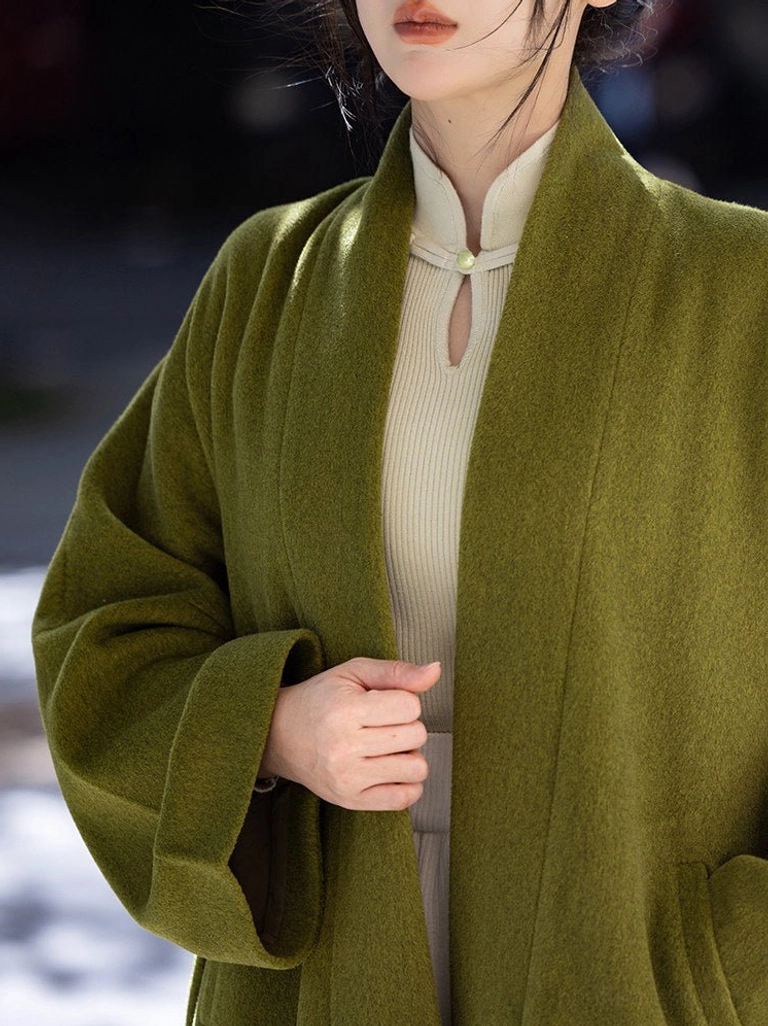 Close up of moss green Song Dynasty Hanfu jacket showing soft textured fabric stand collar jade frog button and side pocket