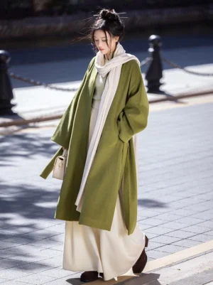 Full body side view of a woman wearing a moss green Song Dynasty Hanfu jacket with matching wide leg pants on an urban street