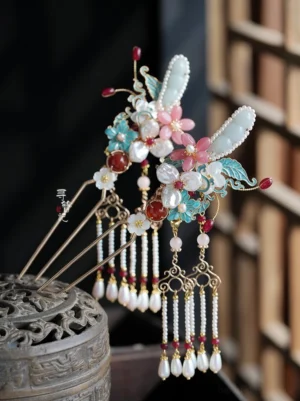 Oblique close-up of matching Hanfu side hanging hairpins with pink flowers blue cloisonne-style leaves imitation jade red beads and pearl tassels displayed on an antique Chinese incense burner