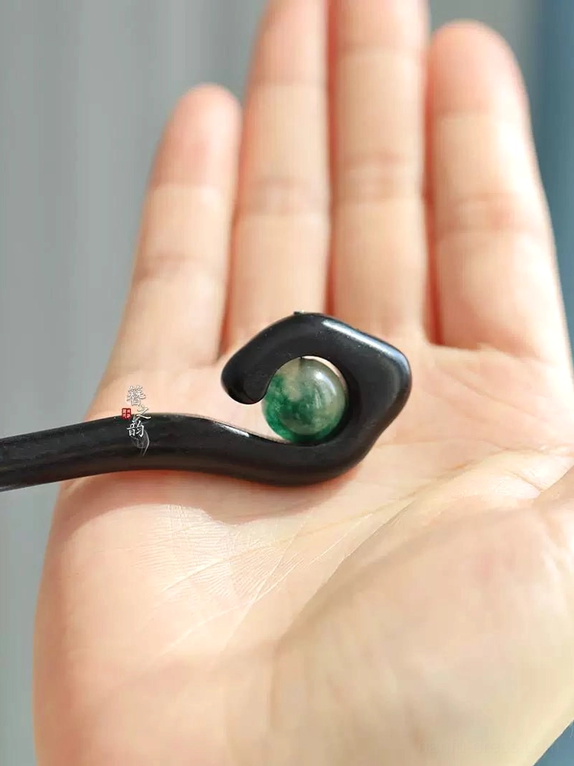 Mountain Spirit Chinese hair stick displayed on palm for scale with black wood body and green marbled accent