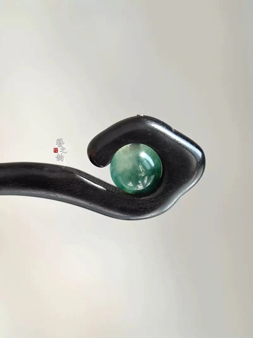 Close-up top view of Mountain Spirit traditional Chinese hair stick in polished black wood with green marbled decorative bead