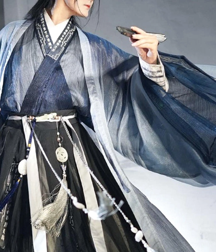 Close up of Mystical Gateways wuxia hanfu for men showing embroidered cross collar dark blue inner top waist belt jade pendant beads tassels and folding fan