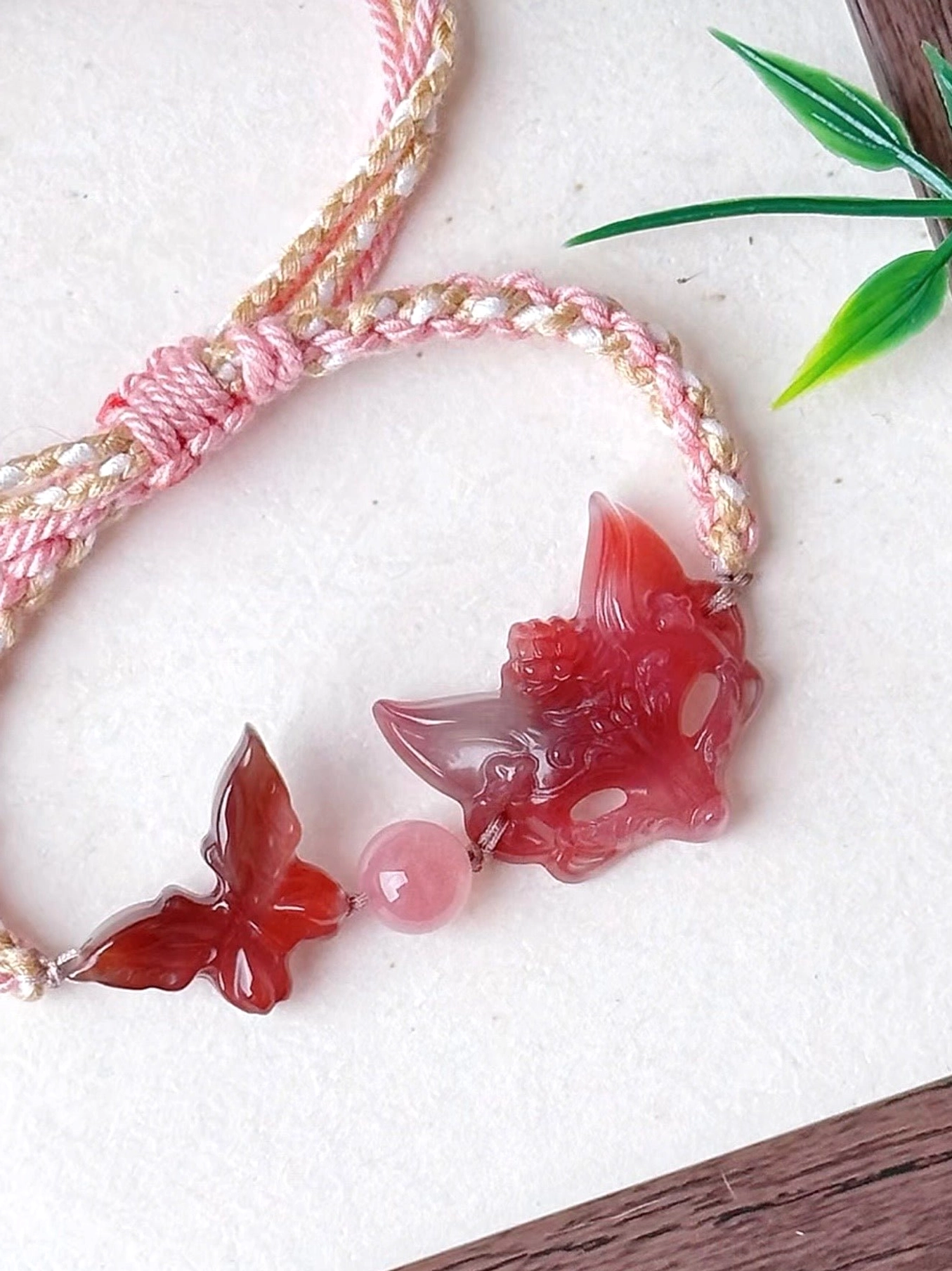 Close-up of natural agate fox spirit Chinese bracelet showing floral carved fox pendant, dimensional red agate butterfly, adjustable braided knot and tassel details