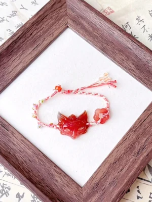 Red agate fox spirit Chinese bracelet with hand-braided pink and white cord, colorful beads, carved fox pendant, cloud charm, and vintage Chinese calligraphy background