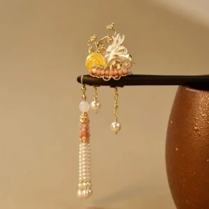 Nine-tailed fox Chinese hair stick with black wooden pin, white shell fox carving, gold filigree, pink beads, pearls and flowing tassels beside ceramic jar