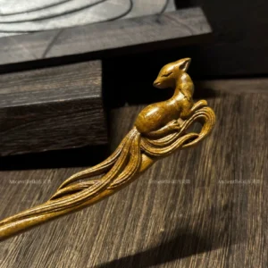 Close-up of the carved fox head and openwork nine tails on a chestnut brown wooden Chinese hair stick for Hanfu hairstyles and fantasy-inspired updos