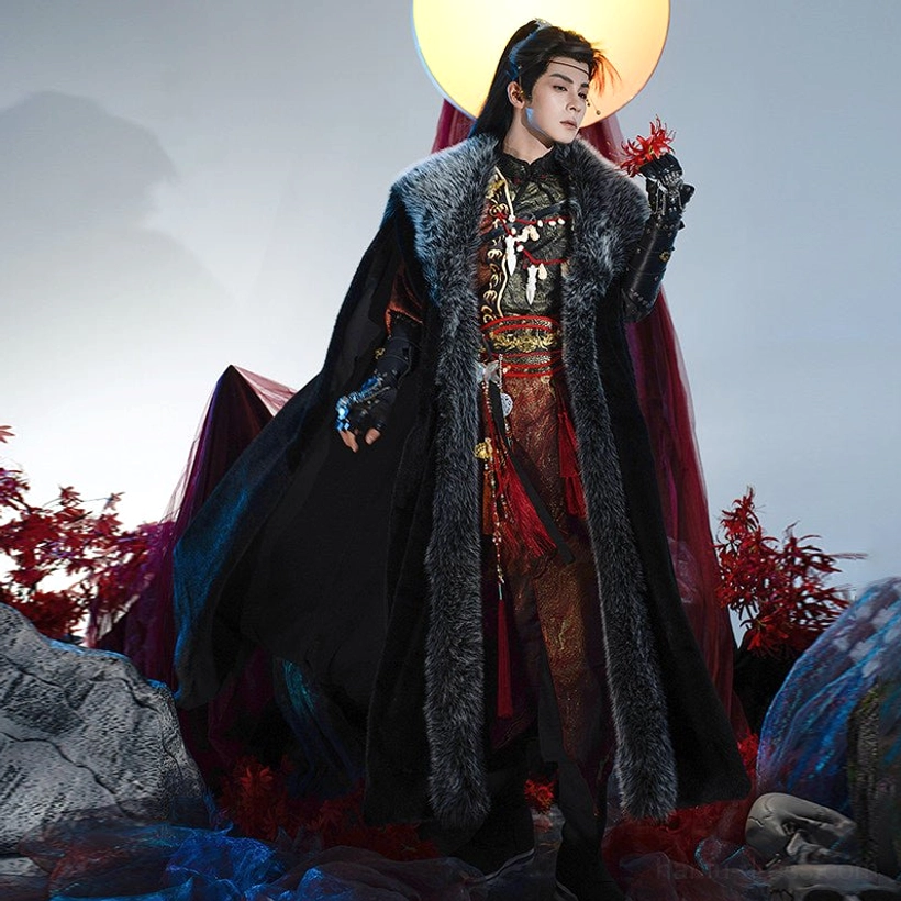 Male model wearing a noble wuxia hanfu costume with embroidered red and gold inner layers and a long black cloak with gray faux fur trim