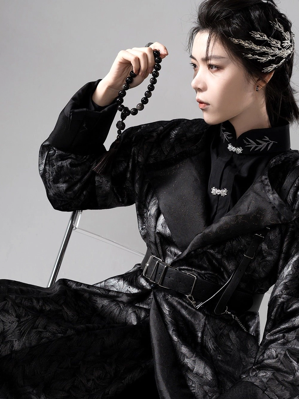 Close-up side view of Tang Dynasty inspired black hanfu robe featuring embroidered collar, silver decorative buckles, textured jacquard fabric, and wide belt