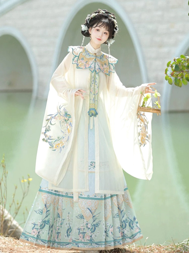Off-white and light blue Ming Dynasty Hanfu outfit with embroidered robe and mamian skirt styled beside a stone arch bridge with a traditional Chinese hair ornament