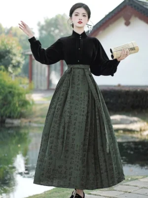 Front three-quarter view of an olive green Chinese calligraphy mamianqun set with black velvet stand-collar top and lantern sleeves in a classical waterside courtyard