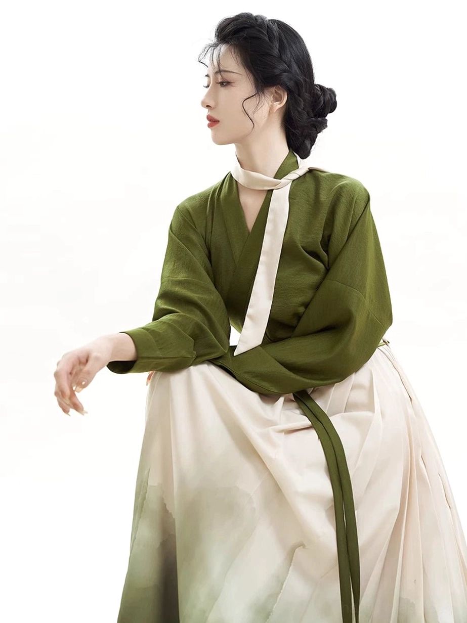 Close-up of the olive green cross-collar Hanfu blouse, neck sash, and upper pleats of the landscape-print skirt