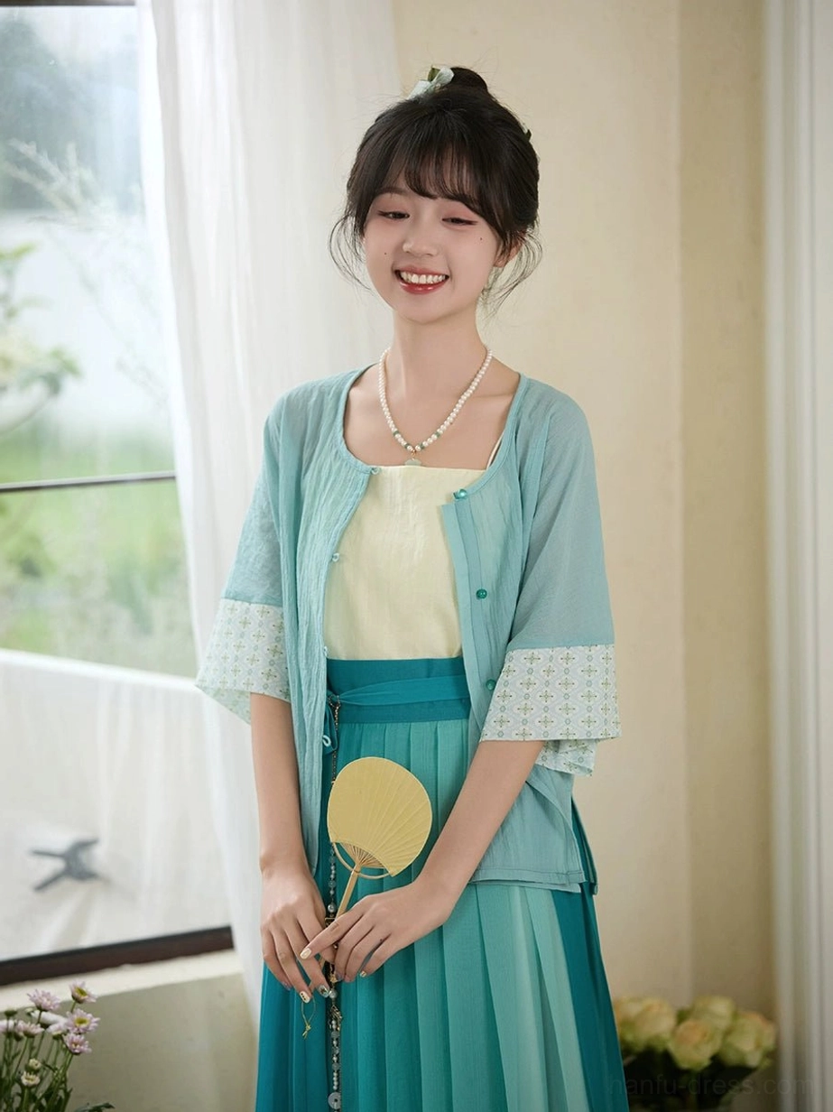 Ming Dynasty inspired New Chinese Style Hanfu showing ivory camisole cyan blouse and long teal pleated skirt with round fan