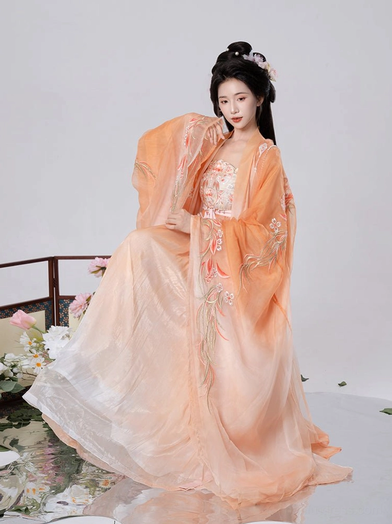 Orange gradient Tang Dynasty Hanfu Heziqun dress shown in a seated portrait with floral embroidered sleeves, long flowing skirt, soft sheer fabric, and flower hairpins