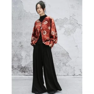 Front full-body view of an orange-red floral velvet modern Hanfu jacket with Chinese frog buttons and loose bat sleeves styled over a black turtleneck and wide-leg trousers