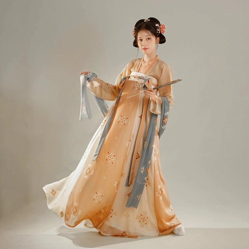 Side view of a model wearing a flowing orange Tang Dynasty Qixiong Ruqun Hanfu dress with floral prints and long sleeves