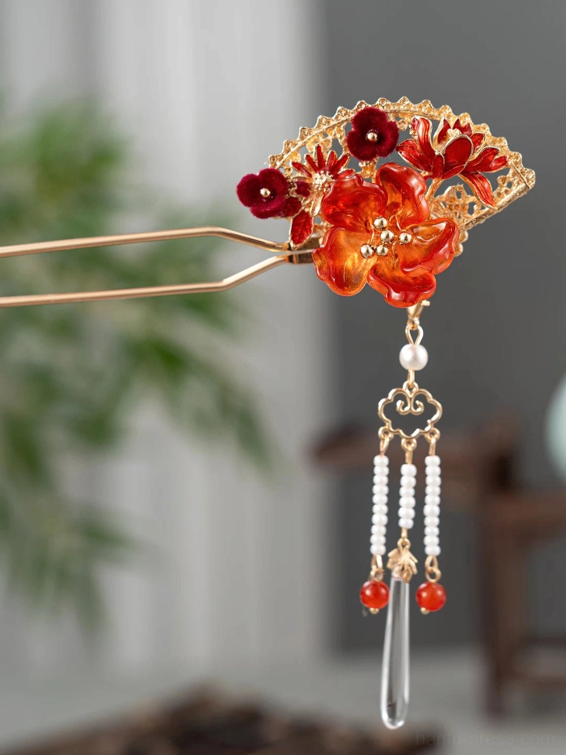 Full view of double pronged Chinese hair stick featuring an openwork fan red orange flowers and long decorative tassels