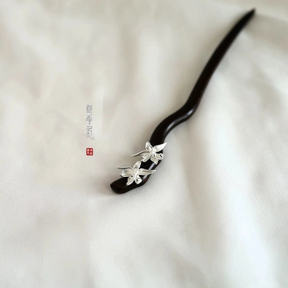 Elegant oriental floral hair stick featuring a dark curved wooden body and silver flower decoration viewed from the side