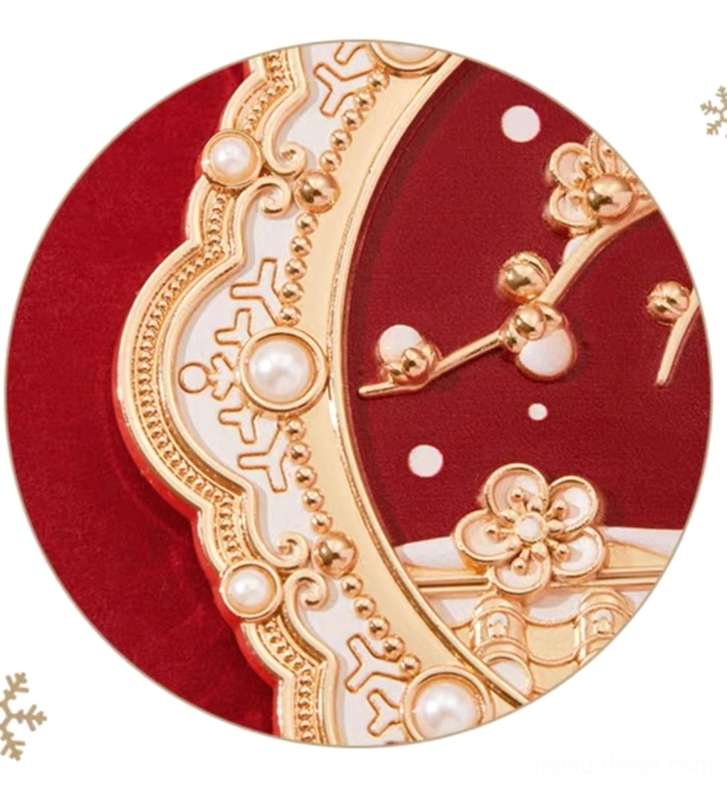 Close-up of ornate Chinese hand mirror frame with carved gold retro patterns, faux pearls, white decorative accents, and plum blossom ornament on deep red velvet