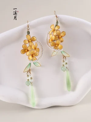 Osmanthus flower Chinese hook earrings displayed on a white ceramic tray with gold floral clusters pearl-style circles green enamel leaves and long jade-look drop pendants