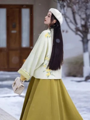 Side back view of cream osmanthus embroidered winged sleeve Song Dynasty inspired Hanfu jacket in a snowy winter street setting