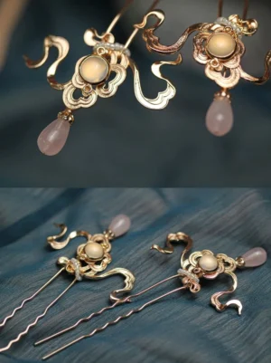 Pair of matching Zheyue Chinese hair pins with gold cloud ornaments and dangling pink drop charms displayed on dark blue fabric