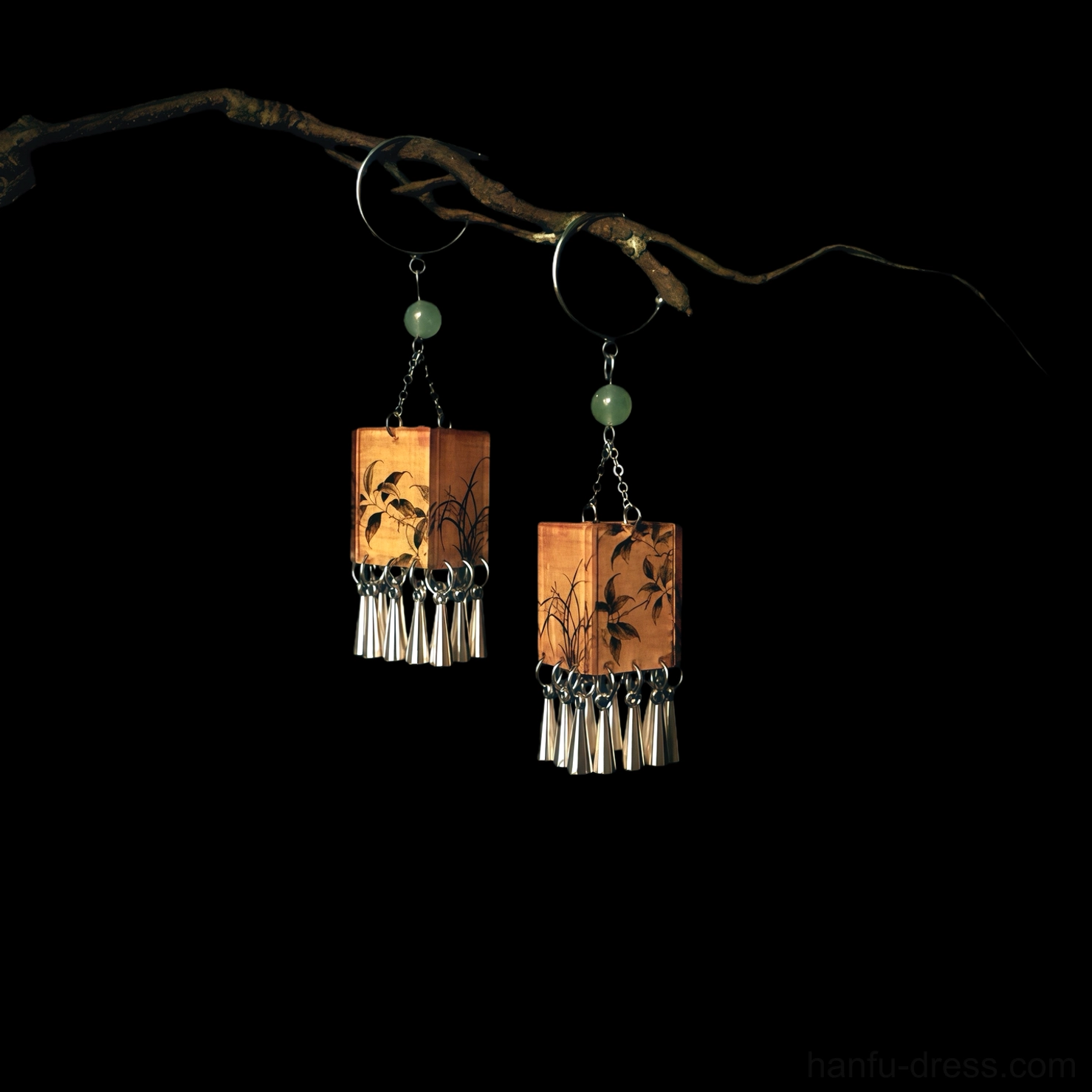 Palace lantern orchid tassel Chinese earrings hanging on a dry branch against a black background