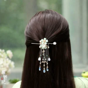 Pale green floral Hanfu back hair pin with delicate metal frame, blue glass droplet tassels, and flower detail styled with a light green traditional Chinese outfit in a garden