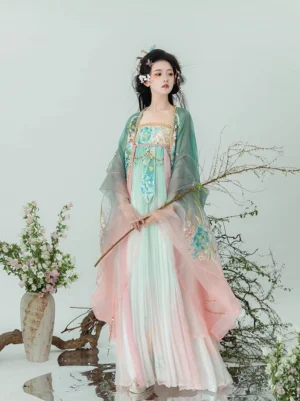 Pastel pink and green Tang Dynasty Qixiong Ruqun Hanfu set shown from a three quarter front view with floral embroidery and sheer green big sleeve coat