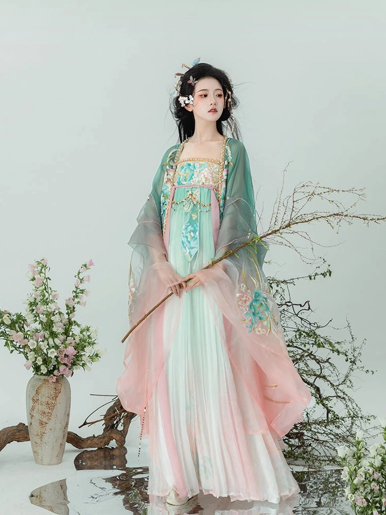 Pastel pink and green Tang Dynasty Qixiong Ruqun Hanfu set shown from a three quarter front view with floral embroidery and sheer green big sleeve coat