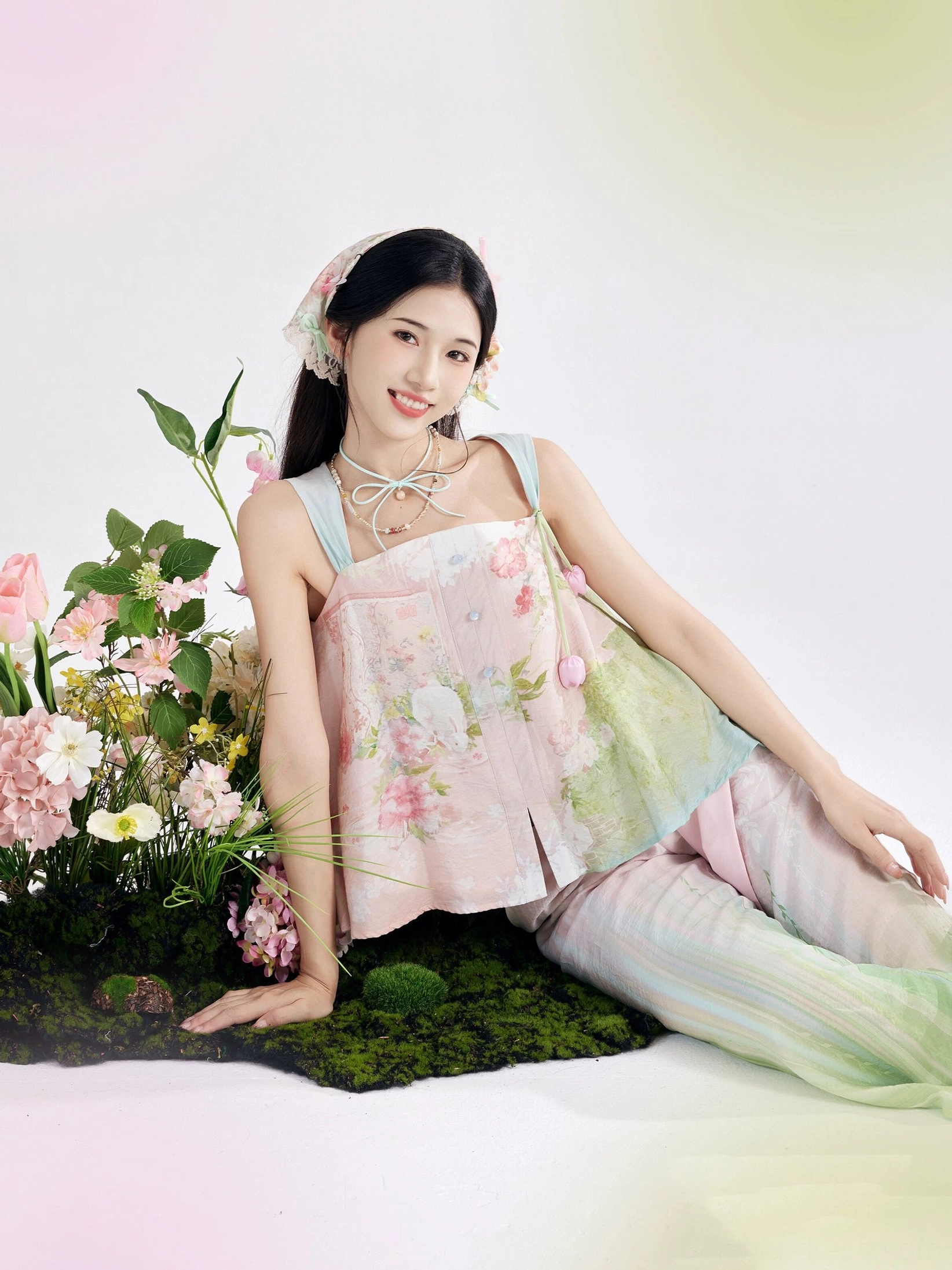 Smiling model wearing a pastel floral modern Tang Dynasty Hanfu outfit with soft gradient colors, flower hair accessories, and relaxed garden-inspired styling