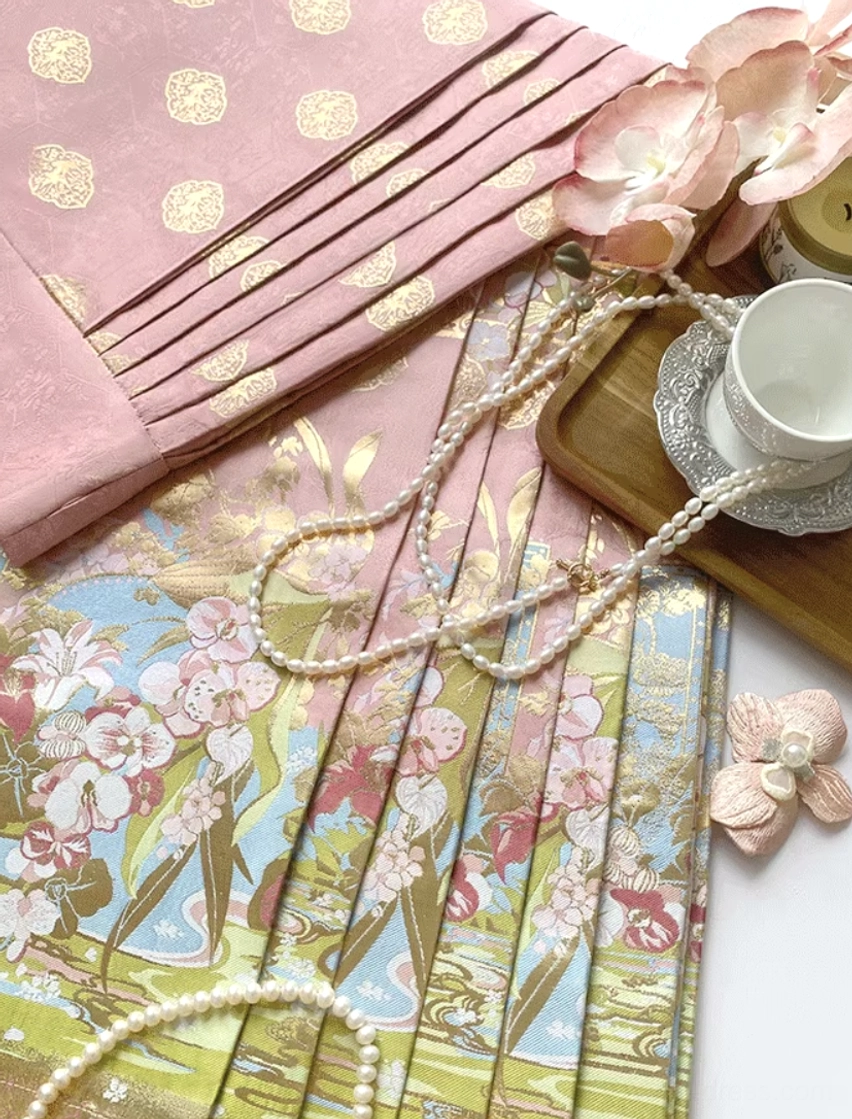 Close-up detail of pastel modern Hanfu mamian skirt fabric with floral panels, gold embroidery, and matte texture