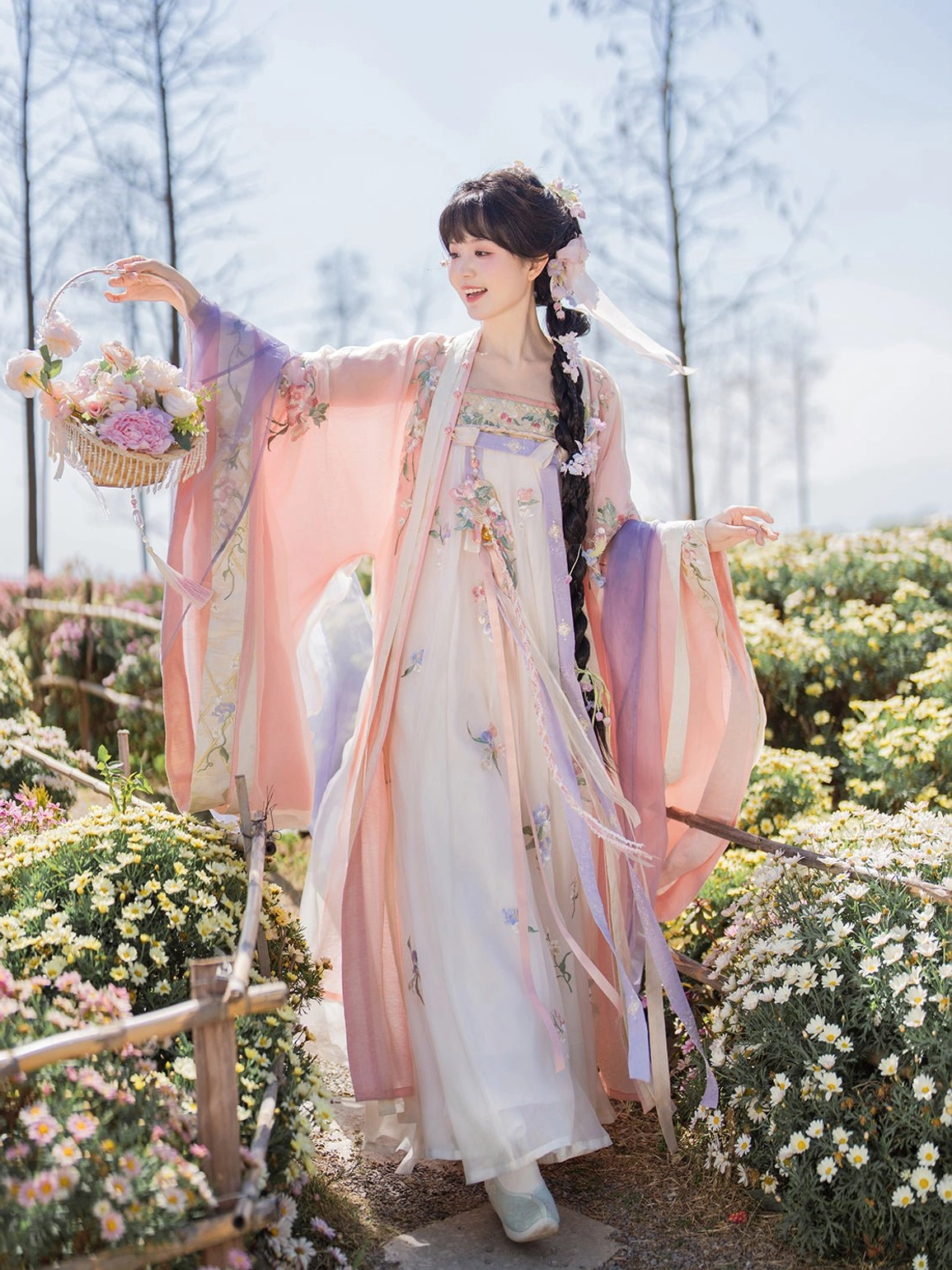 Pastel pink and lilac Tang Dynasty Qixiong Ruqun hanfu dress with floral embroidery and wide sleeves modeled in a flower garden