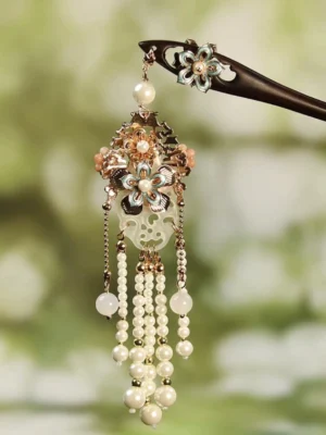 Traditional Chinese floral tassel hair stick with black wooden shaft, enamel flower ornament, pink flower pendant, carved jade-inspired charm, pearl tassels, and gold-tone chains against a soft green background