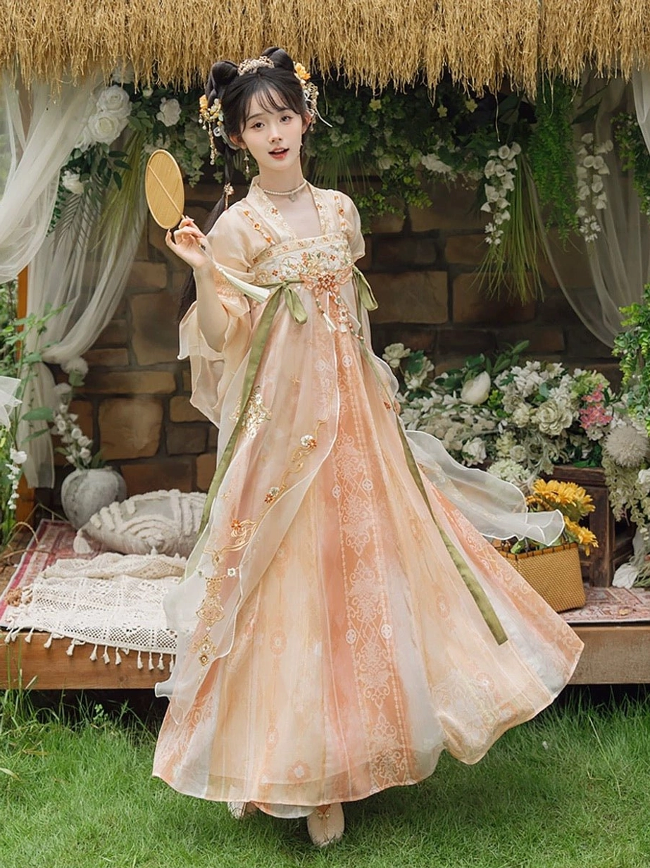 Three-quarter side view of peach-apricot chest-high Hanfu dress with flowing long skirt, green silk-look waist sashes, floral embroidery, and romantic Chinese garden styling